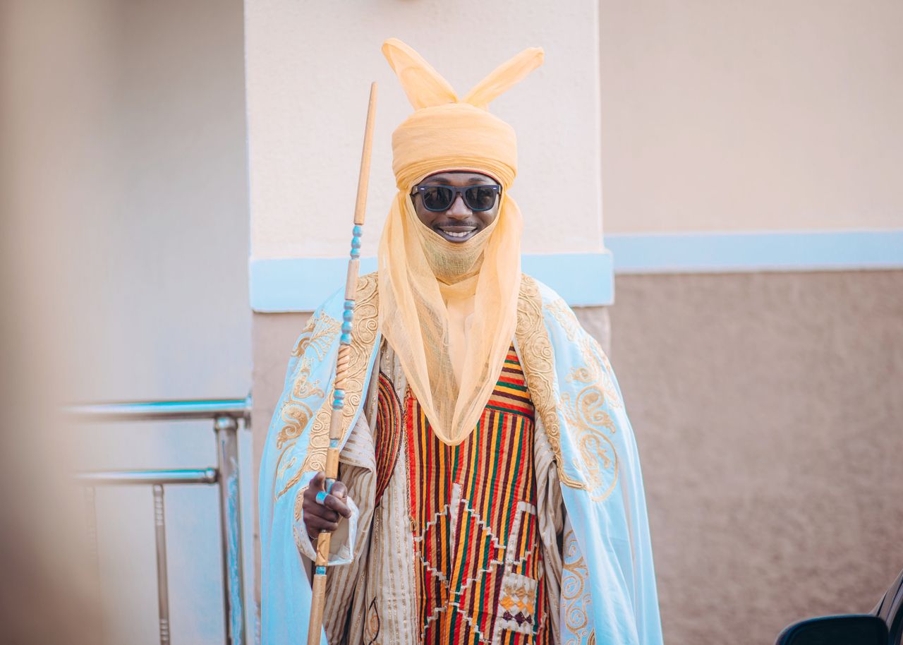 Man in vibrant traditional clothing holding a staff, showcasing cultural heritage.